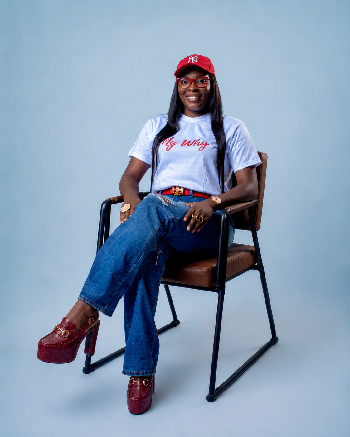 Theresa Power seated and smiling in a My Why T-shirt, red cap, and jeans